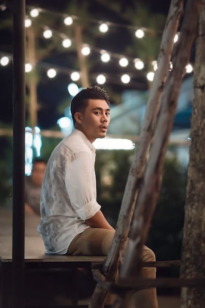 A portrait of Justin Chang, a man with a focused gaze, in a setting that hints at cultural engagement, possibly a film festival or an outdoor cafe.