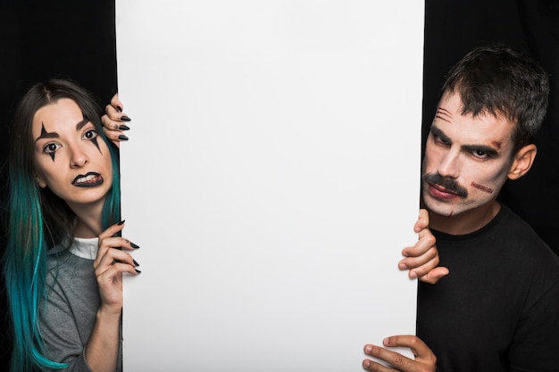 A split image showing two different movie reviewers holding up different genre labels (e.g., comedy vs. drama) in front of the same movie poster.