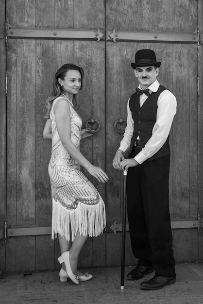 Black and white photo of Charlie Chaplin in a classic pose from one of his silent films. He is wearing his iconic bowler hat and holding a cane, with a mischievous expression on his face. The image evokes a sense of nostalgia and timeless physical comedy.