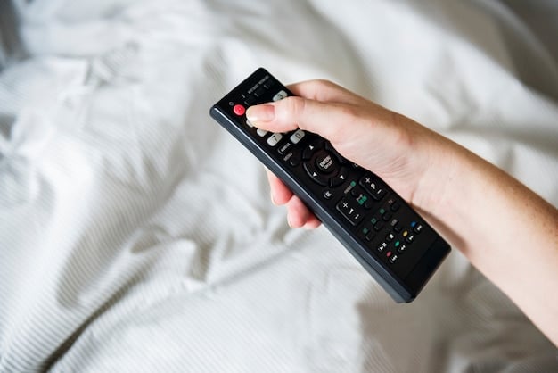 Close-up of a TV remote control with fingers pressing the power button, reflecting a sense of uncertainty and decision-making about what to watch. The background is blurred, showing various streaming service logos.